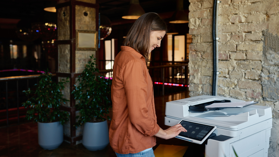A woman is using a copier in a modern office.