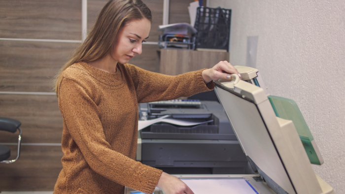 A woman is contentedly using a copier in an office.