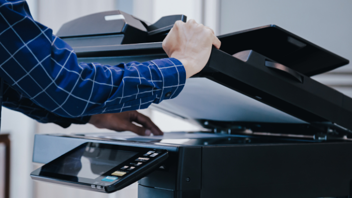 Person lifts a printer lid to copy a document.