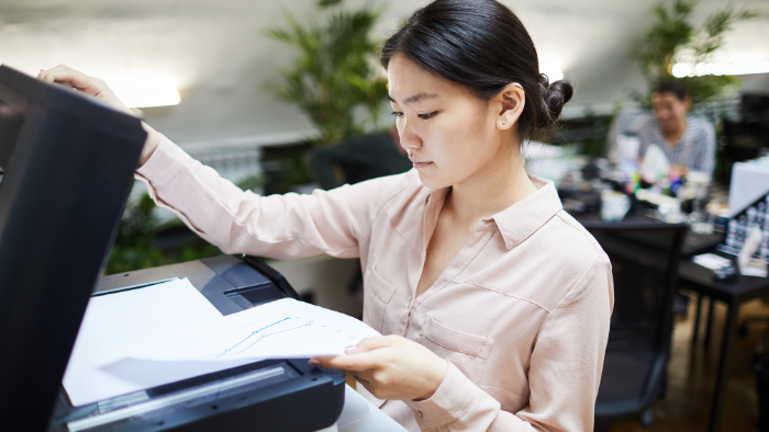 A woman uses a copier in an office.