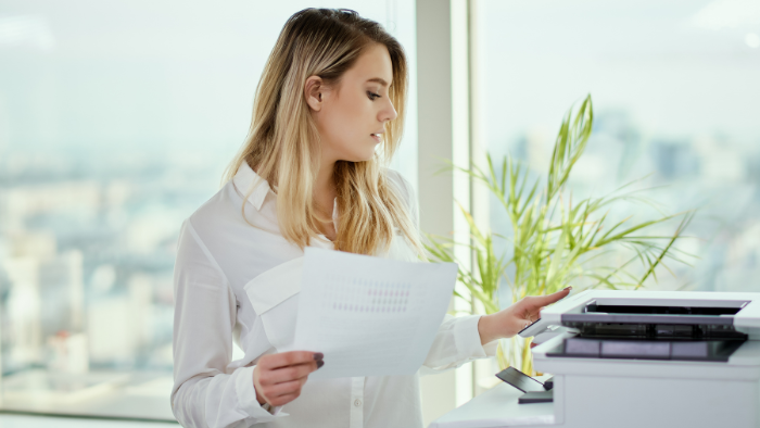 A business woman prepares to copy a document on her office printer.