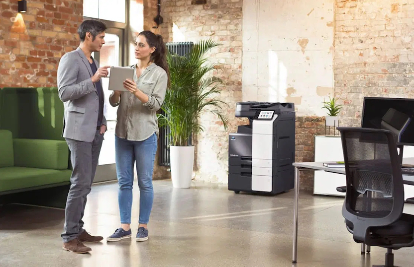 two people talking in front of office printer