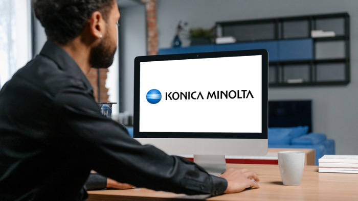 An office worker looks at a computer screen with the Konica Minolta brand displayed