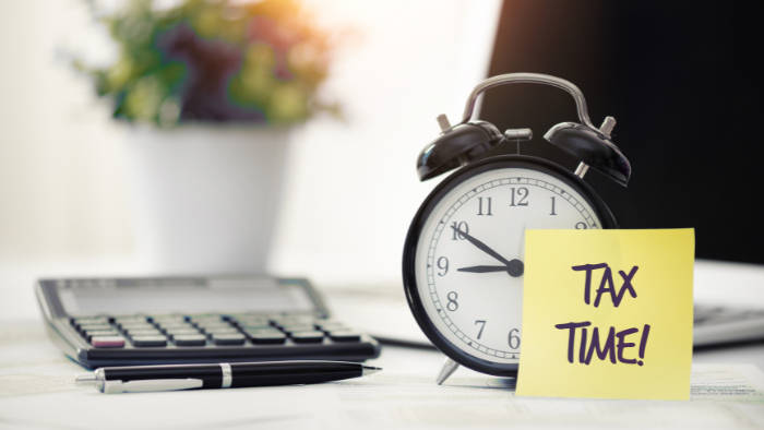 A clock and a calculator with a sign that reads, "tax time." Leasing a printer can help with tax savings.