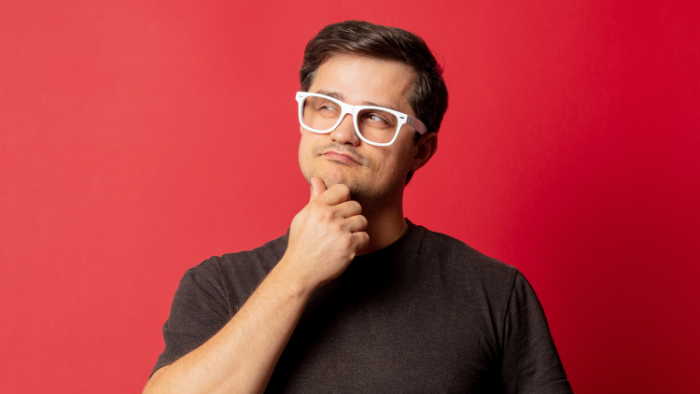 A man with white glasses poses in a thinking posture