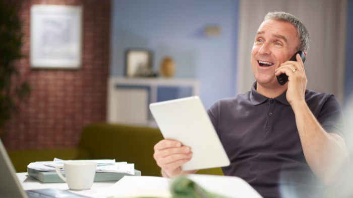 Man talking on phone in office while holding a tablet