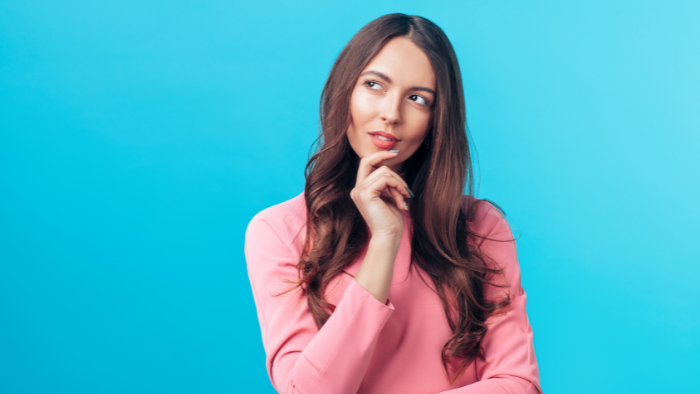 Woman in a pink sweater thinking about whether an office printer lease is right for her business.